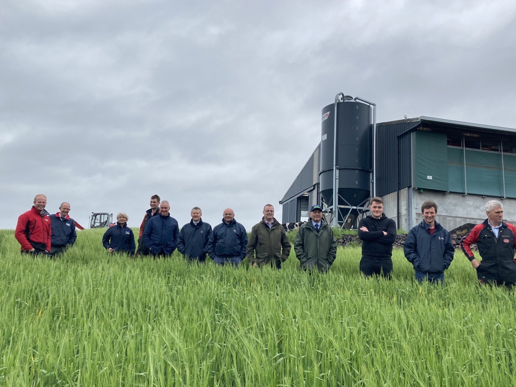 Low Ballees steering group stood in a line in a crop field in front of the cow shed
